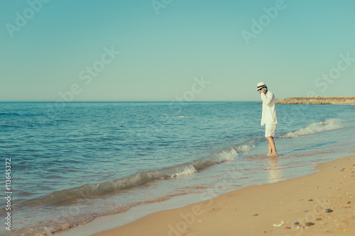 Young stylish man on the phone walking on beach