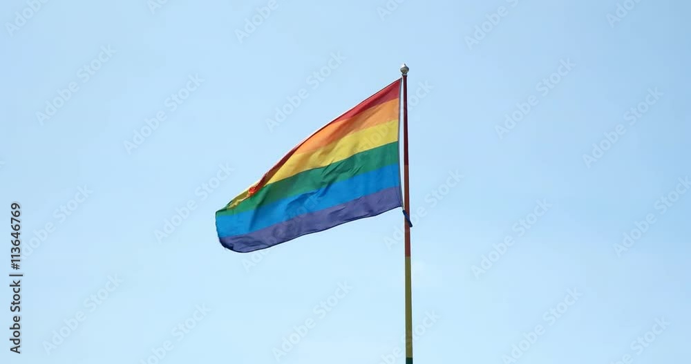 Gay pride flag mid screen against blue sky Gay pride flag mid screen against blue sky
