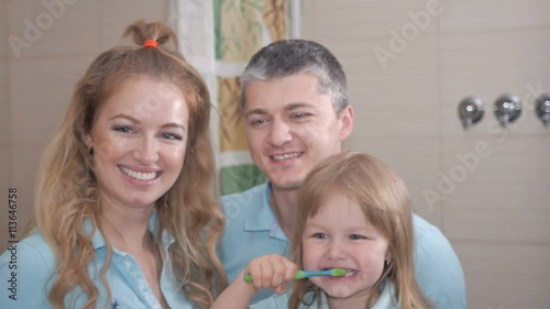 Mother and father teaching little daughter clean teeth photo