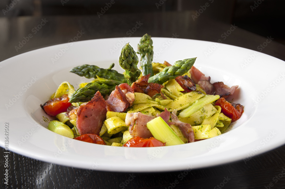 Asparagus salad with pasta, pesto, grilled cherry tomatoes and ham