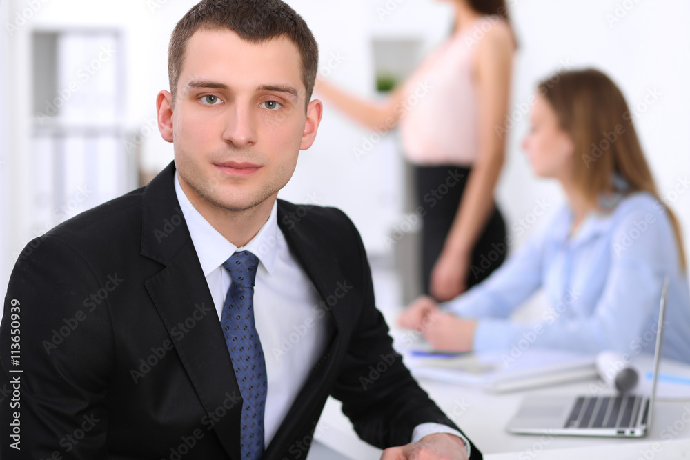 Portrait of a young business man against a group of business people at a meeting. Portrait of a young business man against a group of business people at a meeting.