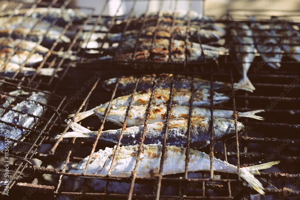 Top view on grilling fish on barbecue, background outdoors 