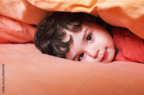 Bambino che sorride sotto il cuscino