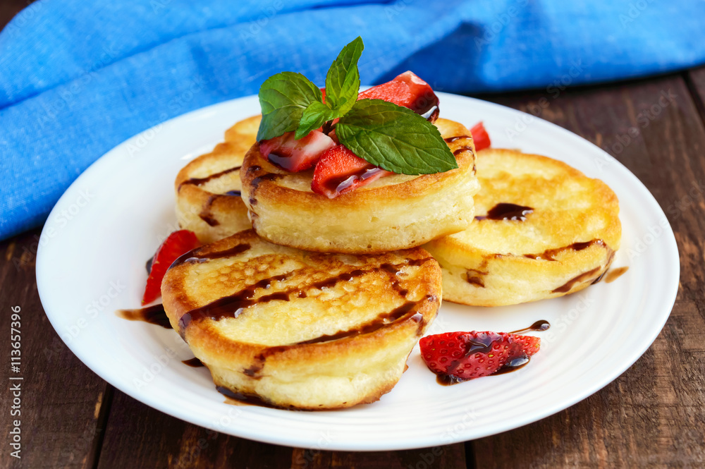 Rustic pancakes with fresh strawberries and chocolate on a white plate. Close-up. Rustic pancakes with fresh strawberries and chocolate on a white plate. Close-up.