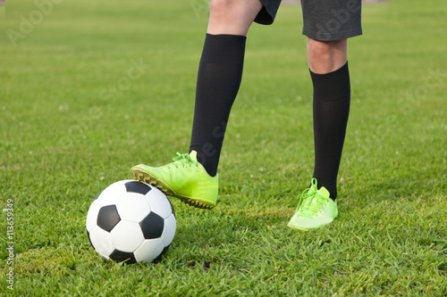 Soccer ball and a football player legs on a green lawn, close-u