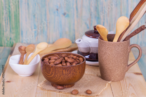 Almonds in brown bowl on textured wooden background
