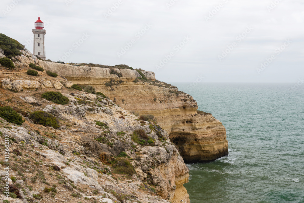 Coastal view along the Seven Hanging Valleys Trail with Farol de Alfanzina lighthouse in background, Algarve region, Portugal