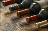 Row of wine bottles with dry red wine on wooden background. Low depth of field. Wine making and wine shop concept.