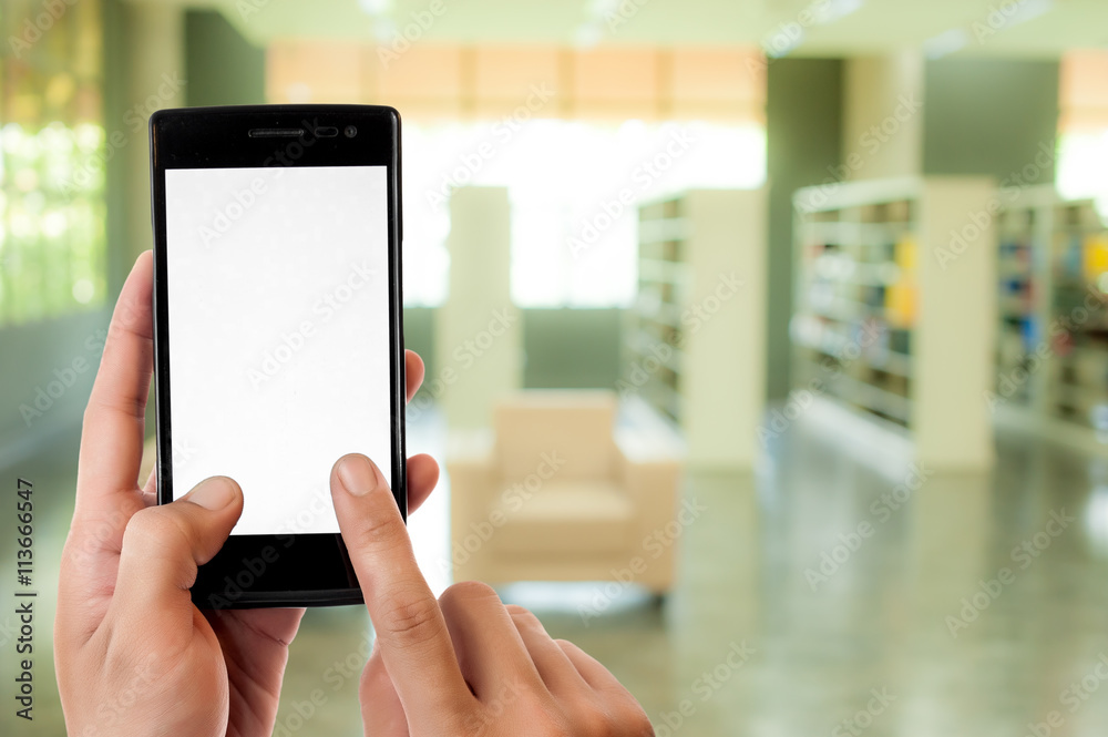 Hand holding smart phone on blur library room background Hand holding smart phone on blur library room background