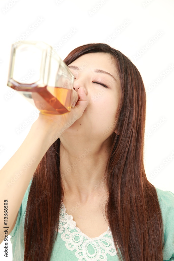 young Japanese woman wearing a green summer dress drinking straight from a bottle