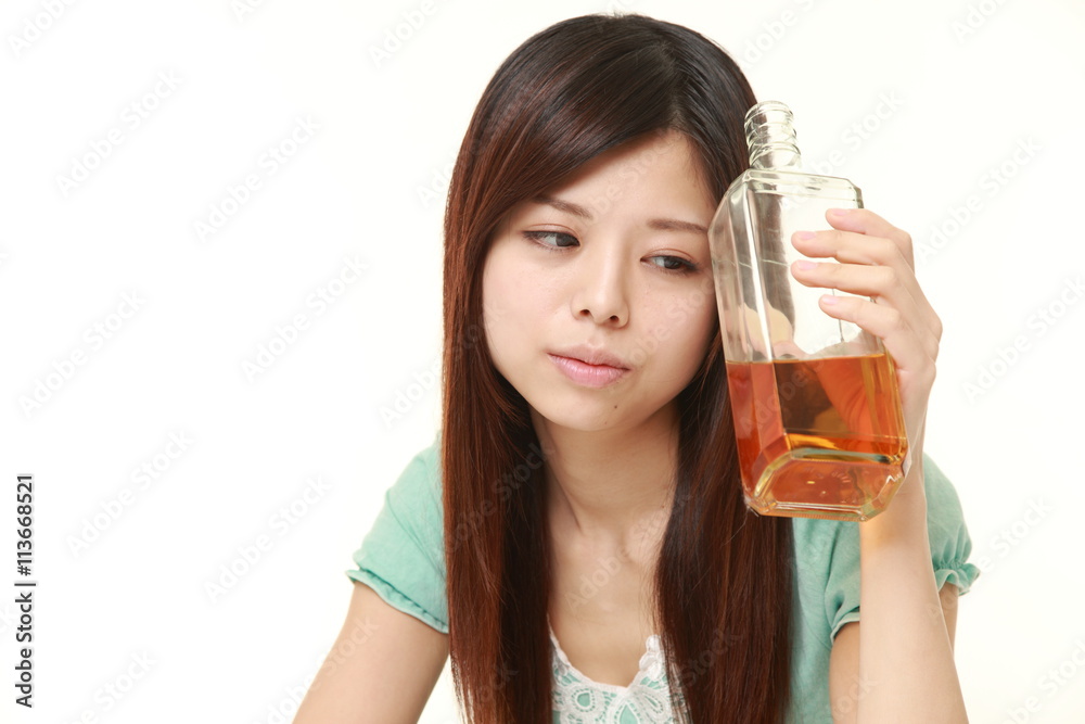 young Japanese woman wearing a green summer dress drinking straight from a bottle young Japanese woman wearing a green summer dress drinking straight from a bottle