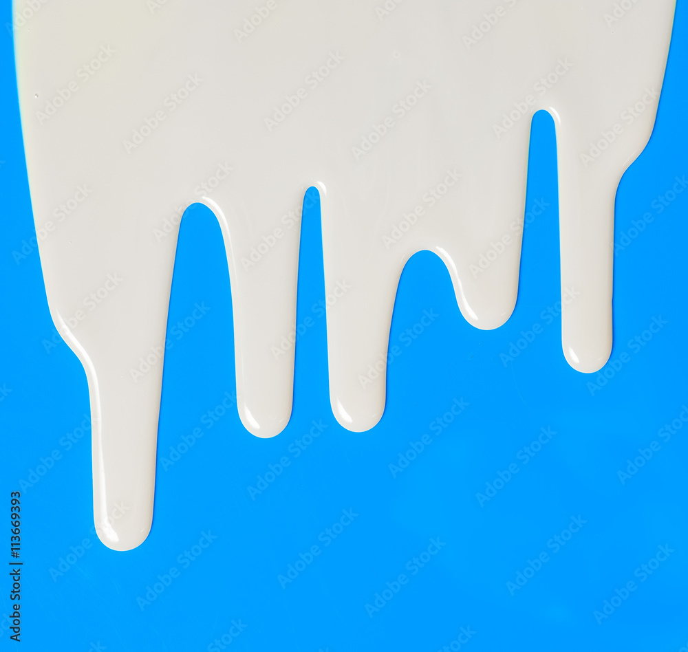 Dripping white milk, cream, paint yogurt on blue background Dripping white milk, cream, paint yogurt on blue background