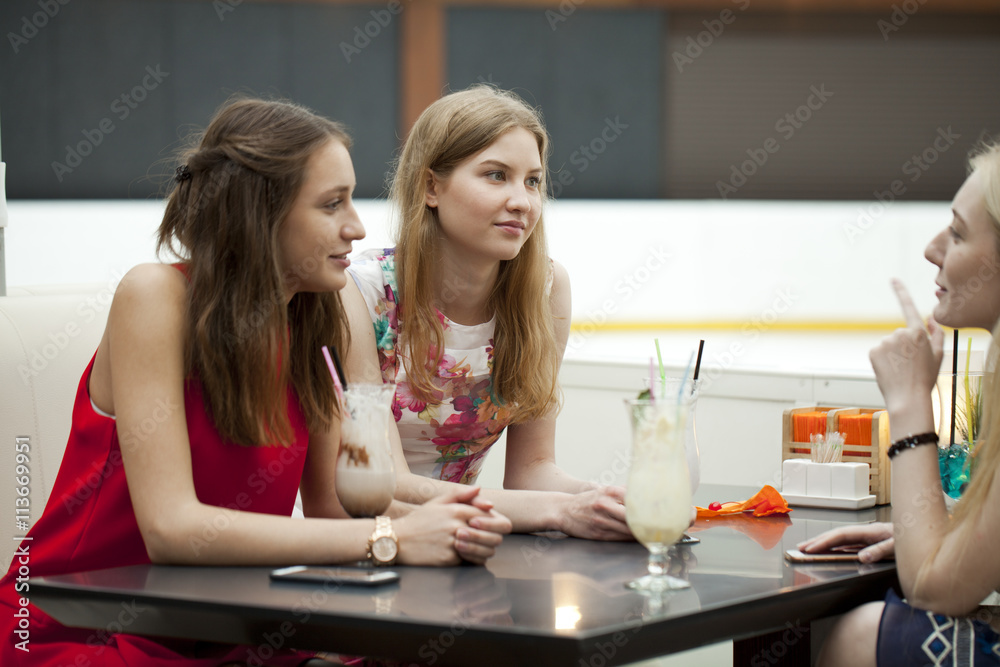 Three young girls sitting in cafe talking