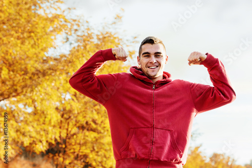 Young handsome man flexing mucles outdoor photo