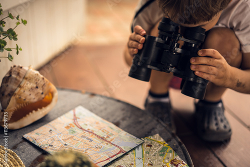 Boy looking through binoculars map on the table