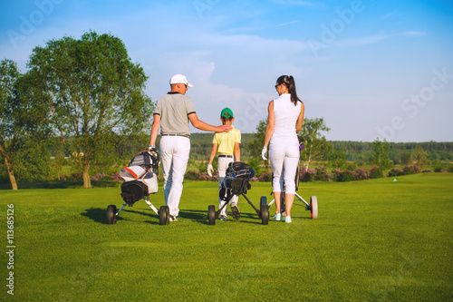 Family golfers plaing golf at sunny day, back view