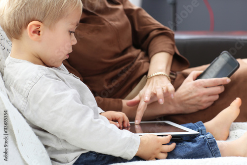 son learning and using tablet with his mother