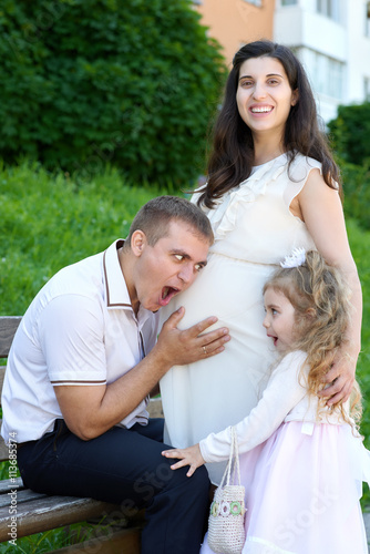 man and child listen belly of pregnant woman, happy family, couple in city park, summer season, green grass and trees © soleg