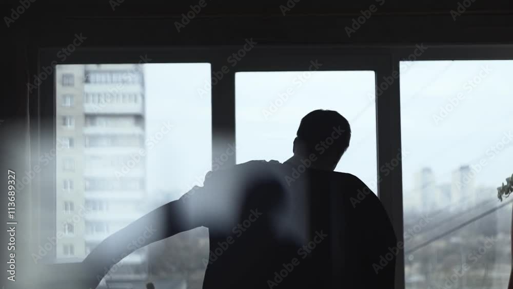 Slow motion shot of a man dressed suit near the window in the room, getting ready for wedding or festive reception