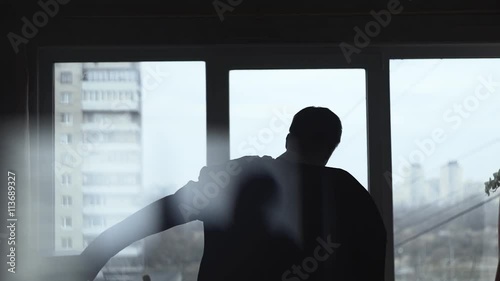 Slow motion shot of a man dressed suit near the window in the room, getting ready for wedding or festive reception