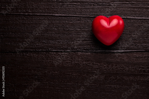Red heart over dark-brown wooden background