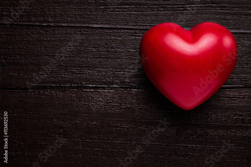 Red heart over dark-brown wooden background