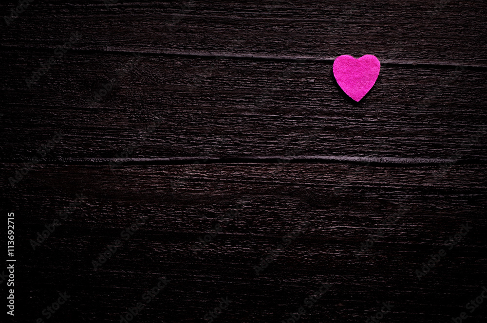 Little pink heart over dark-brown wooden background Little pink heart over dark-brown wooden background