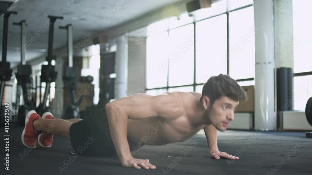 Handsome fitness man doing push ups in gym