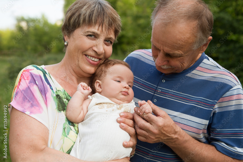 Fototapeta premium the grandmother and the grandfather with the newborn granddaughter walk in park in summer day