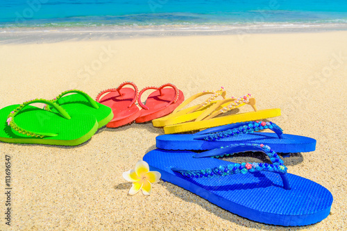 Fototapeta Naklejka Na Ścianę i Meble -  Colored sandals fanned out on a deserted tropical beach.