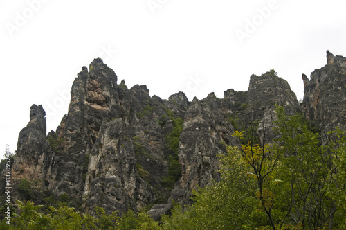 Eroded rocks in mountains against gray cloudy sky background