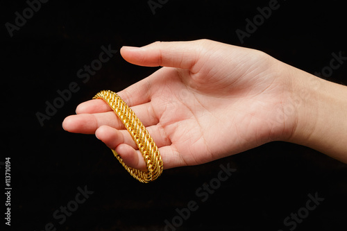 Girl's hands with golden bracelets on a black background