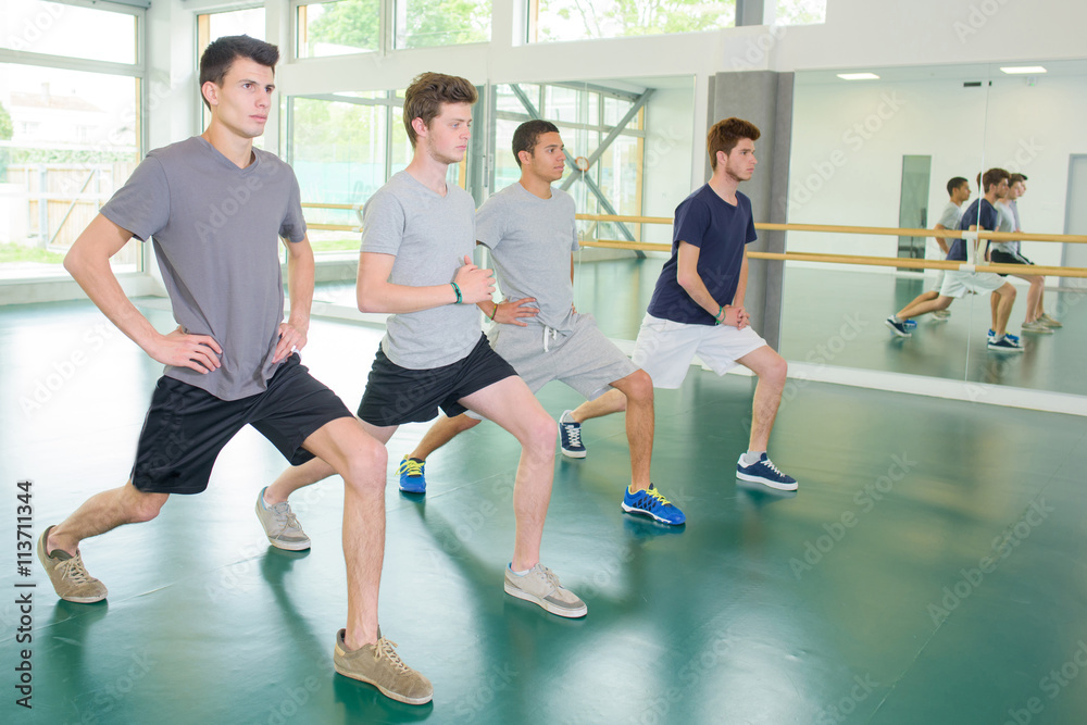 Four young men exercising, stepping forward