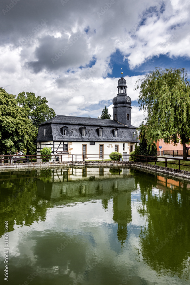 Bucha, Thuringia, Germany: Village church with green, pond and trees