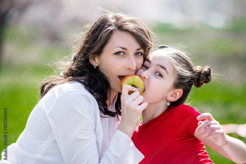 Mother and her child enjoy the early spring, eating apple, happy. Mother and her child enjoy the early spring, eating apple, happy.