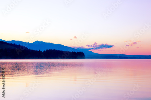 Fototapeta Naklejka Na Ścianę i Meble -  beautiful landscape with mountains and lake at dawn in golden, blue and purple tones.