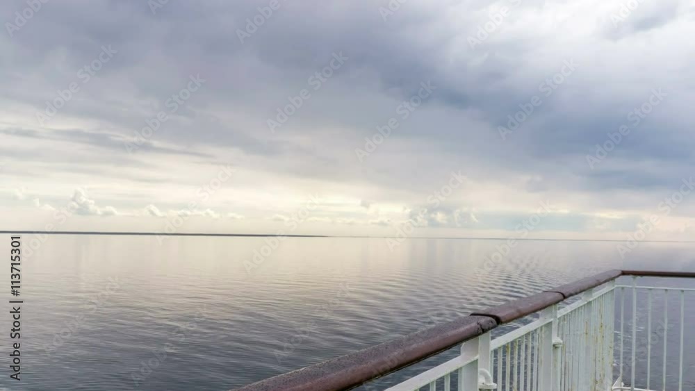 Time lapse backdrop of moody sky in the evening with still water on a boat deck