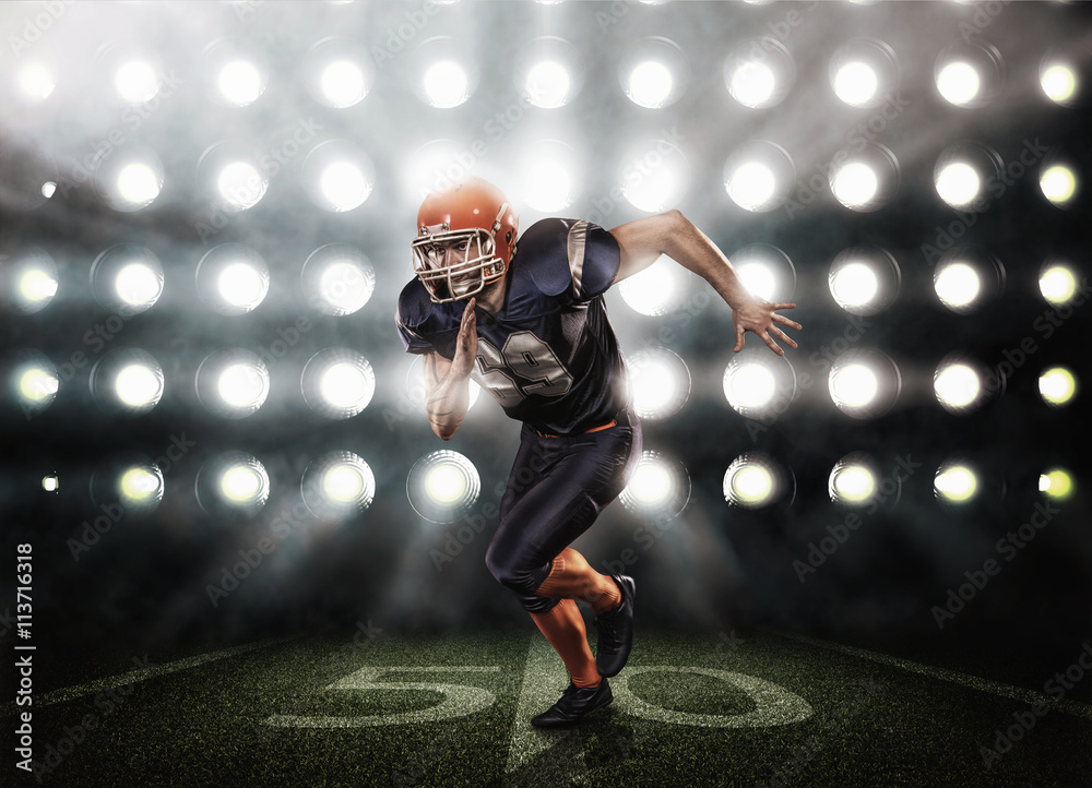 Obraz premium Football player in blue uniform on grass illuminated by floodlights