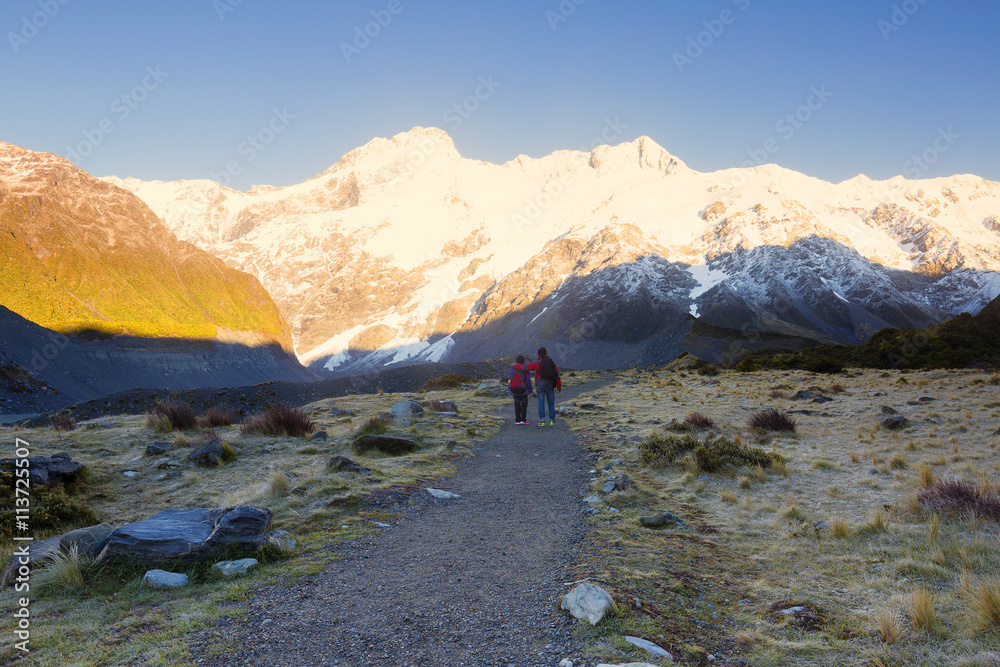 Hikers enjoying the moment mountain peaks illuminated by sun.