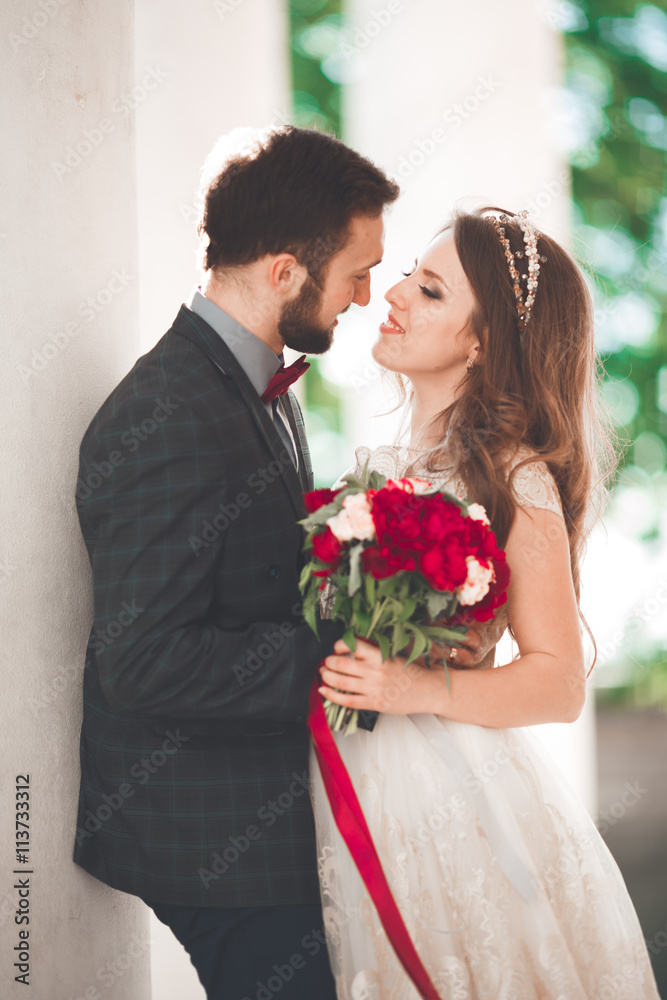 Beautiful couple, bride and groom posing near big white column
