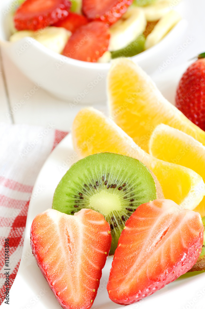 Bowl with fruit salad - pieces of strawberry, oranges, and kiwi Bowl with fruit salad - pieces of strawberry, oranges, and kiwi