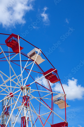 Red and white ferris wheel against a sky