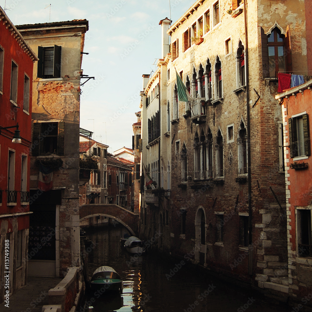 Evening in Venice. Small canal and houses. Aged photo. Street buildings. Toned image. Channels of Venice. Retro filter photo. Italy.