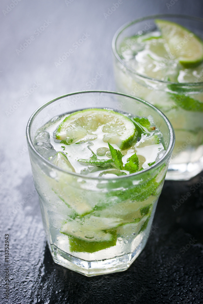 Fresh juicy mojito in glasses on a dark stone background, closeup.