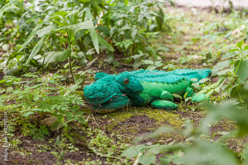Toy green shabby teddy crocodile in the garden.