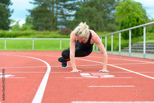Athletic woman warming up hip muscles at track
