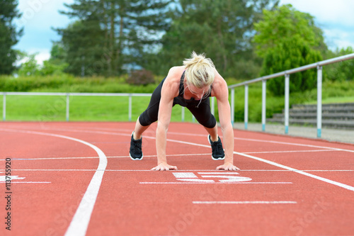 Single woman stretching calf muscles at race track