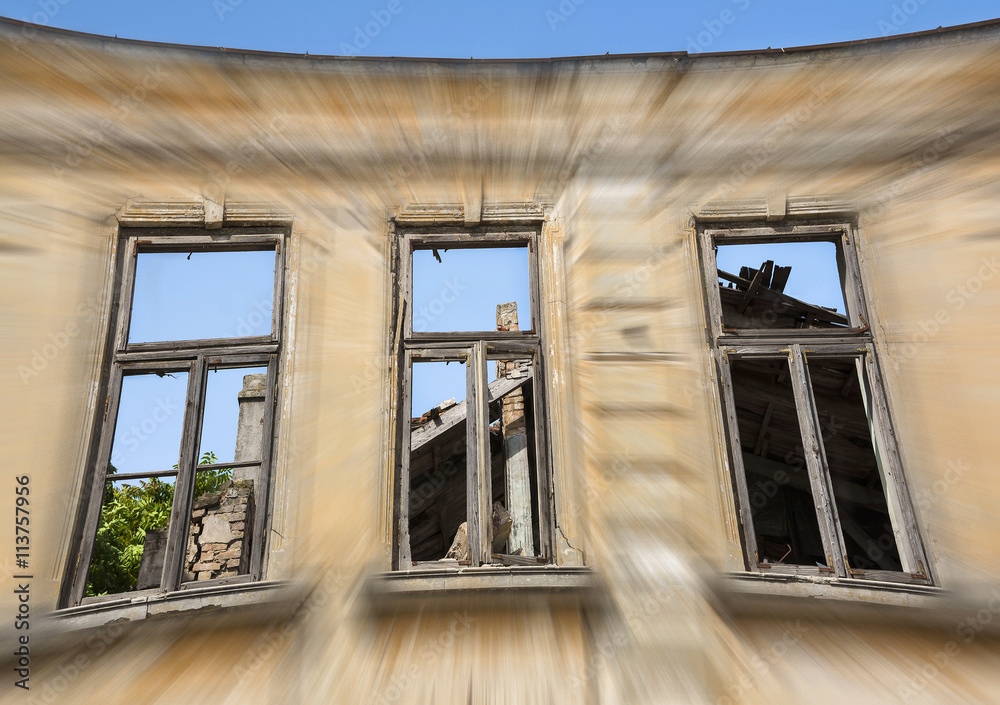 Close up - exterior facade of abandoned house with old wooden windows . Motion blur composition.