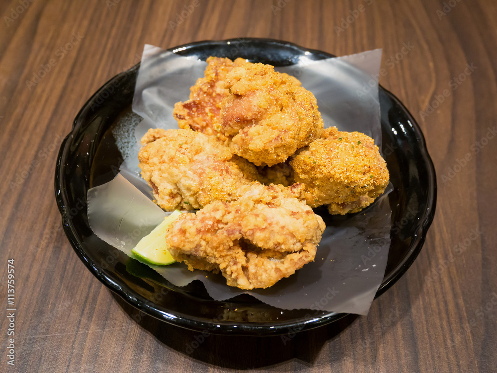 Fresh fried chicken on black plate set on wood table Fresh fried chicken on black plate set on wood table