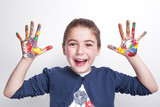 Little girl with arms raised showing painted hands on grey backg